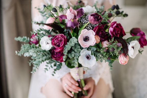 Bridal Blooms A bouquet of mixed flowers, including peonies, anemones, and greenery, held by a person.