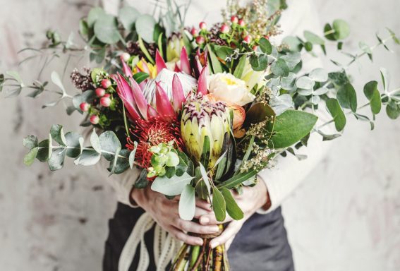 Wild & Wonderful Blooms A person holding a vibrant bouquet of assorted flowers and greenery.