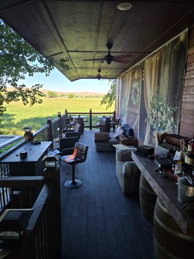 The Upper Deck Lounge A rustic outdoor seating area with wooden furniture overlooking a green landscape.
