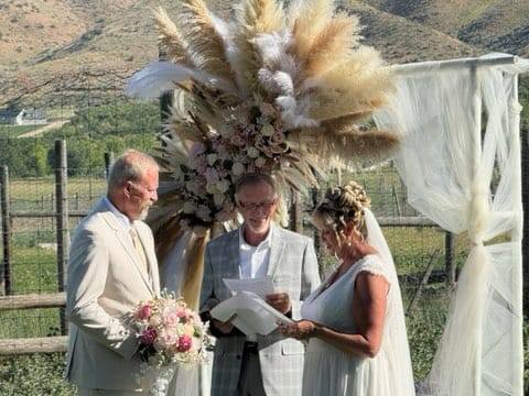 Vows with a View A bride and groom exchange vows outdoors with a decorated backdrop of pampas grass.