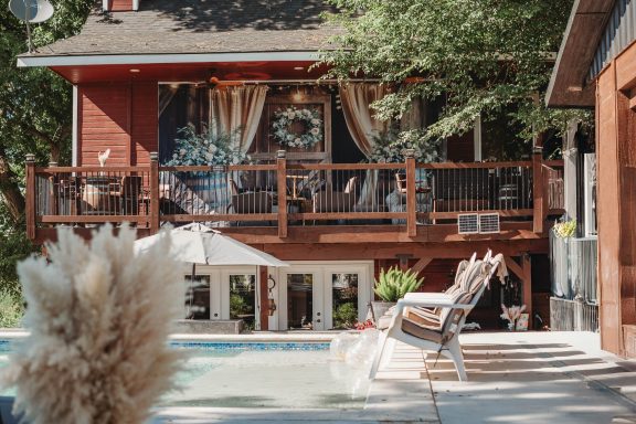 Poolside Charm & Rustic Beauty Modern two-story home with a wooden deck, pool, and outdoor seating.