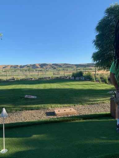 Yard Games with a View A golfer preparing to putt on a green with rolling hills in the background.