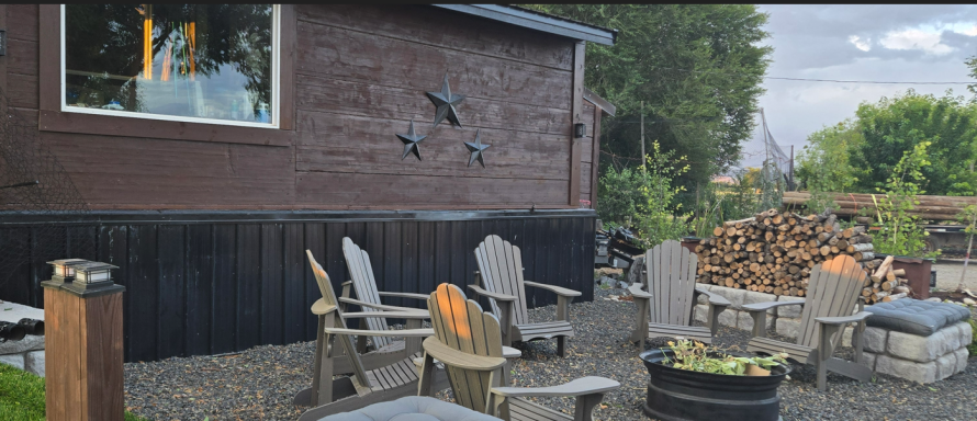 Fireside Simplicity Cozy outdoor seating area with wooden chairs and a fire pit near a brown building.
