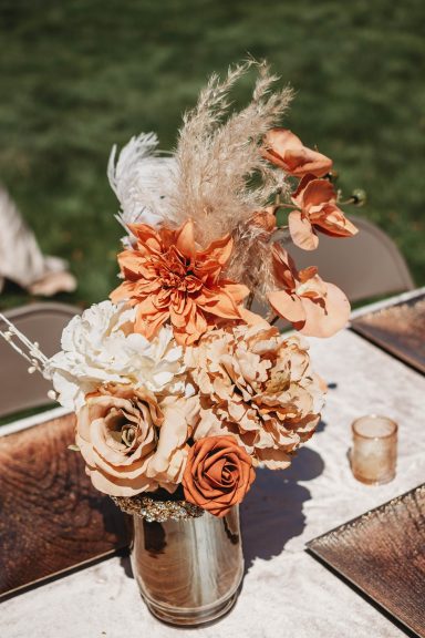 Tabletop Elegance A floral arrangement with orange flowers, pampas grass, and decorative accents in a vase.