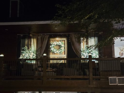 Evening Elegance on the Balcony Decorated windows with a floral wreath and soft lighting on a cozy porch.
